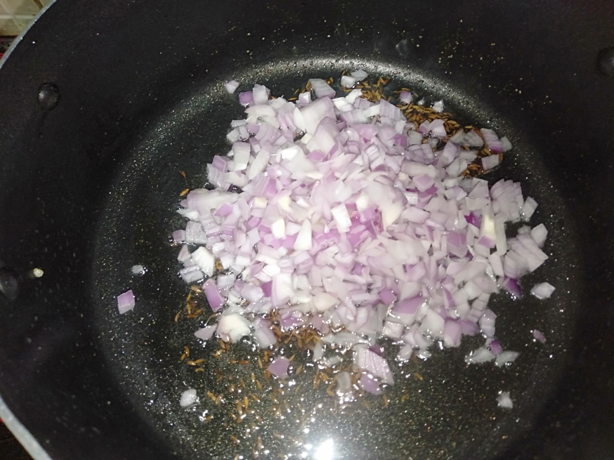 Once the cumin seeds turn golden brown, add the finely chopped onions.