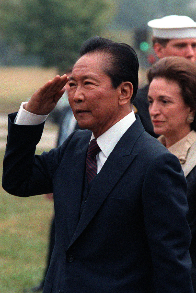 Former President Ferdinand Marcos of the Philippines attends an armed forces full honor departure ceremony with Secretary of State George Shultz.