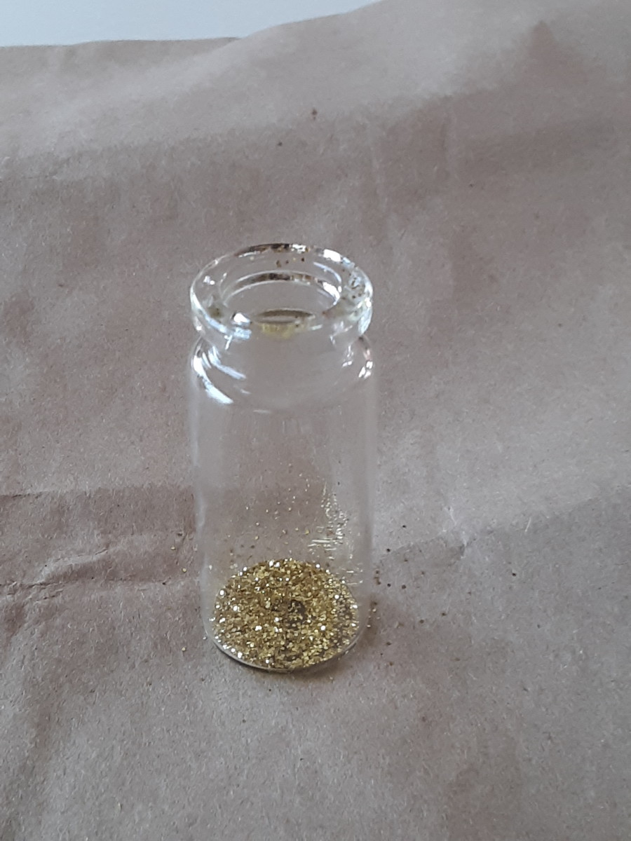 Sprinkle gold glitter inside of the bottle. This step is entirely optional as some may prefer to simply have the mask and rose in the bottle without shimmer.