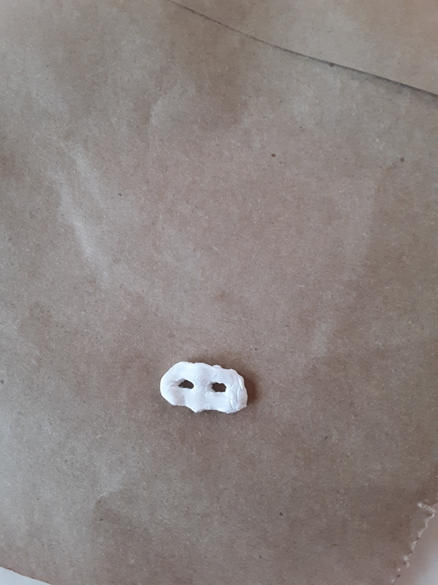 Shape a tiny mask out of white polymer clay. You may also use Sculpy.