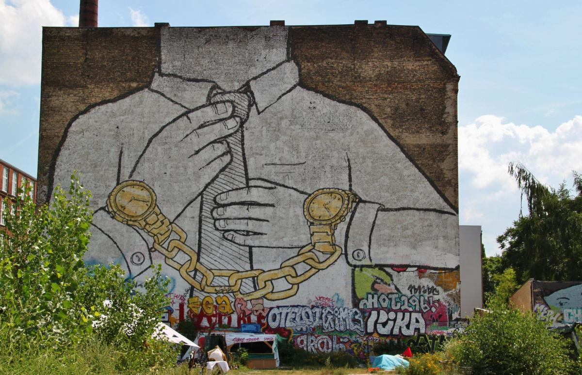A large mural depicts a white collar worker restrained by golden handcuffs.