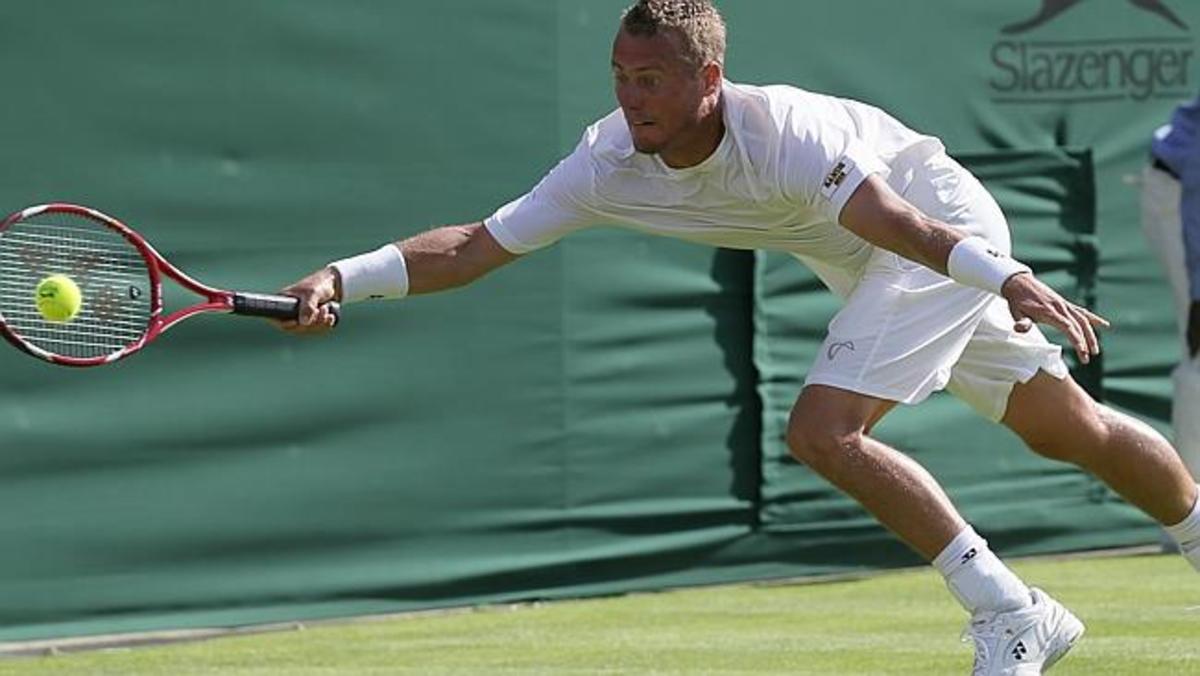 Leyton Hewitt stretches to reach the ball in his 1st round loss at Wimbledon 2015