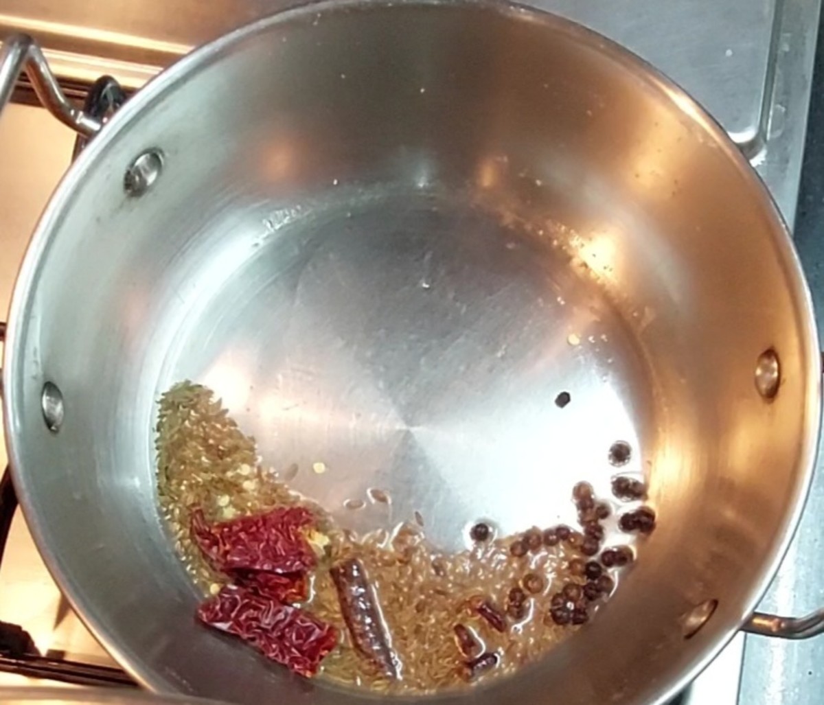 In the same pan, heat 1 tablespoon oil and splutter 1 teaspoon cumin seeds. Add 1/2 teaspoon black peppercorns, a 2-inch-long cinnamon stick, 2-3 cloves and 1-2 broken red chilies. Saute well.