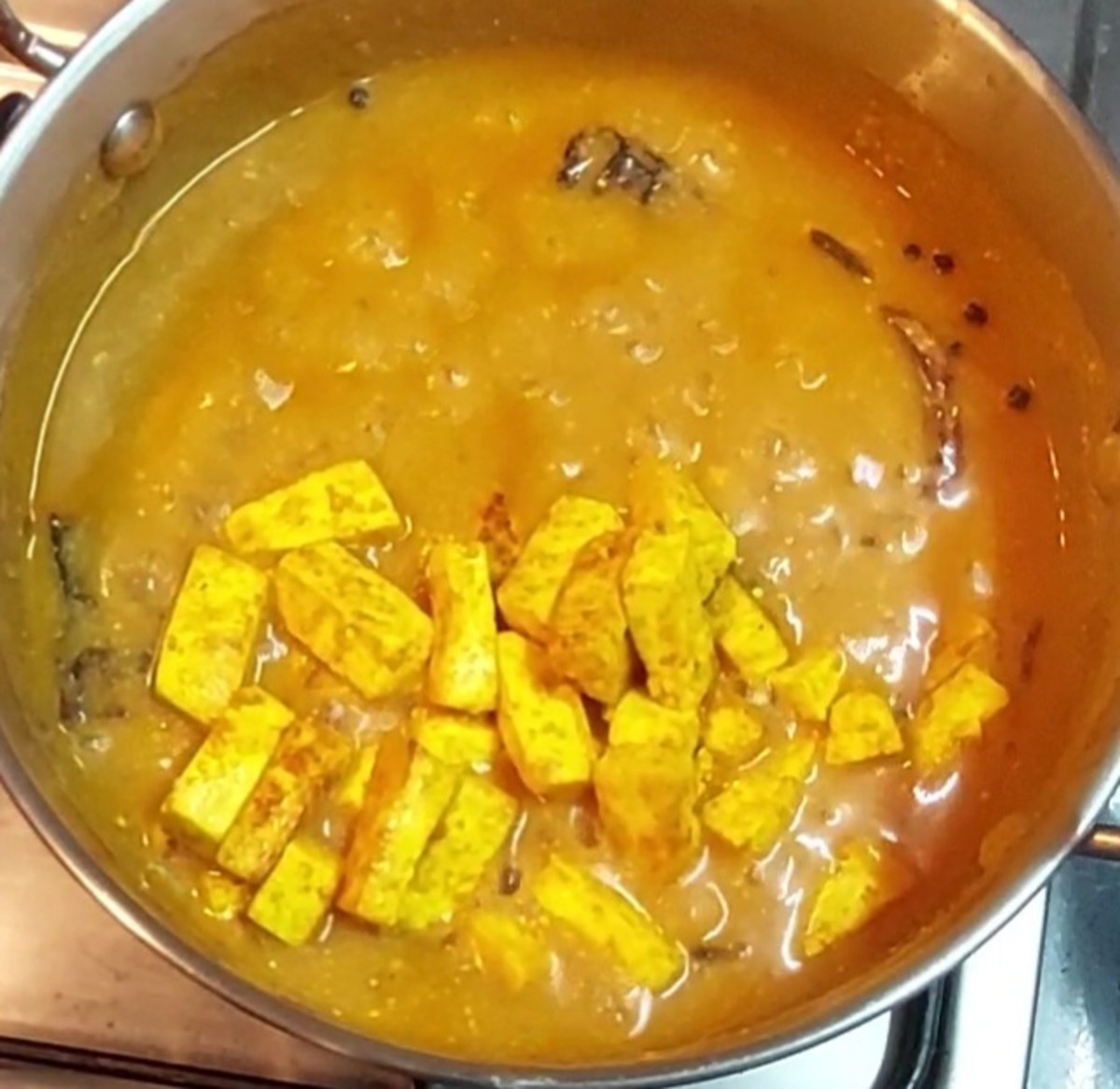 Spread the paneer over the pan and fry over low flame. Flip and fry on other side too. Fry for 5 minutes or till paneer turns golden brown. Switch off the flame. Add the fried paneer pieces to the gravy.