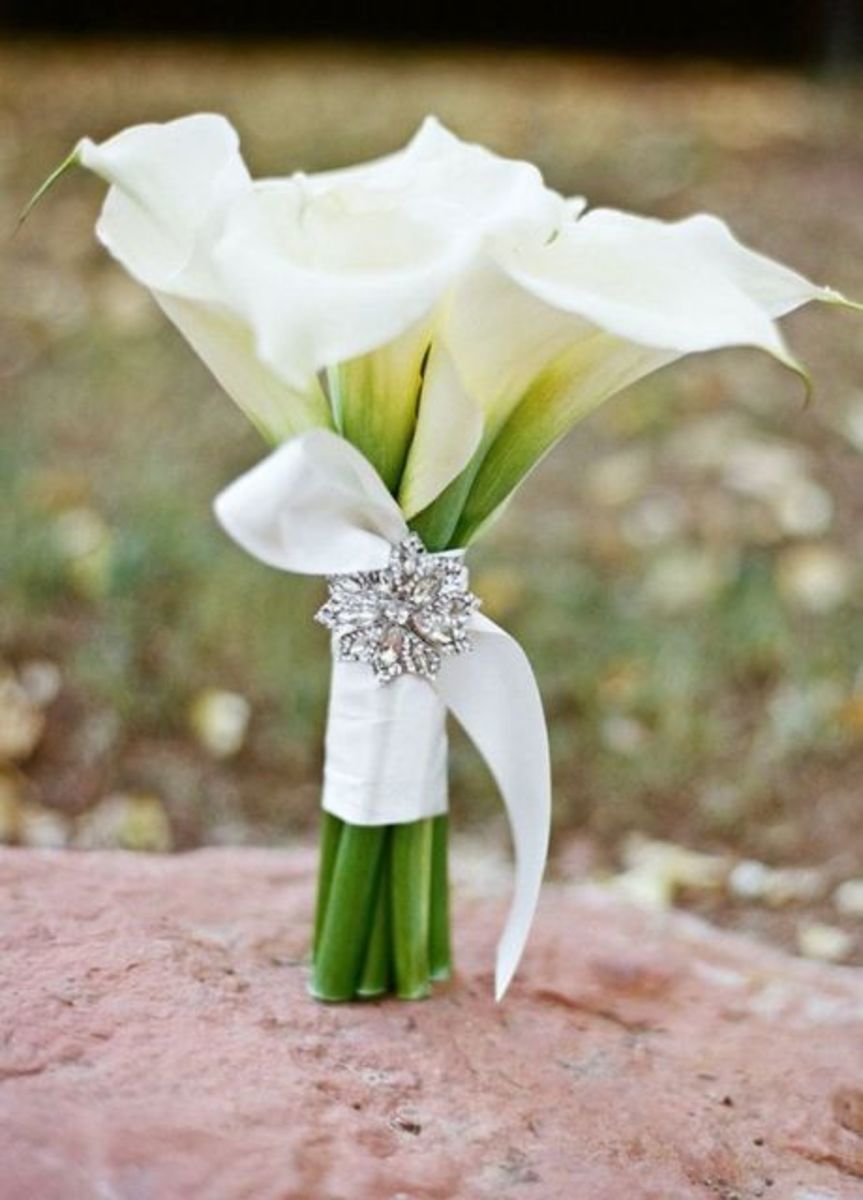 Add an elegant brooch or pin to your wrapped calla lily bouquet