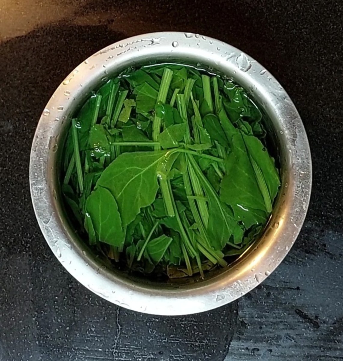 Close the lid and cook for 2 minutes or till palak leaves have shrunk. Switch off the flame. In a vessel, take 2 cups of cold water, add blanched palak and mix.