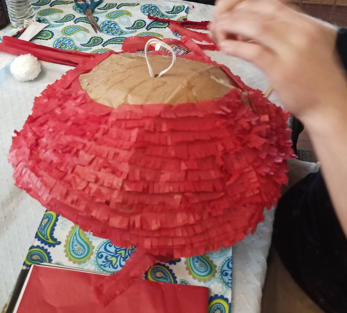 wrap your cut strands of tissue paper around your cardboard body. Make sure you're layering your strips and gluing one piece all the way around the body to prevent gaps in your final product.