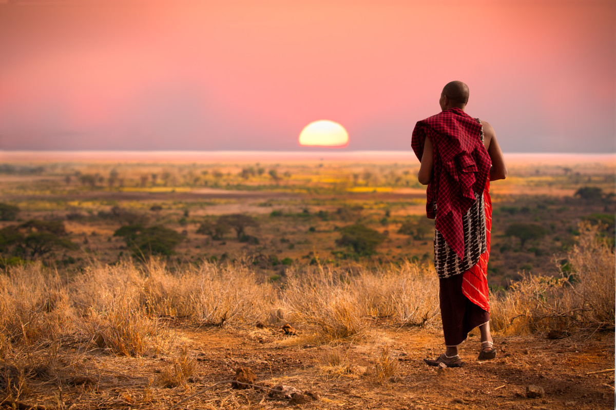 Maasai man, wearing traditional blankets, overlooks Serengeti in Tanzania.