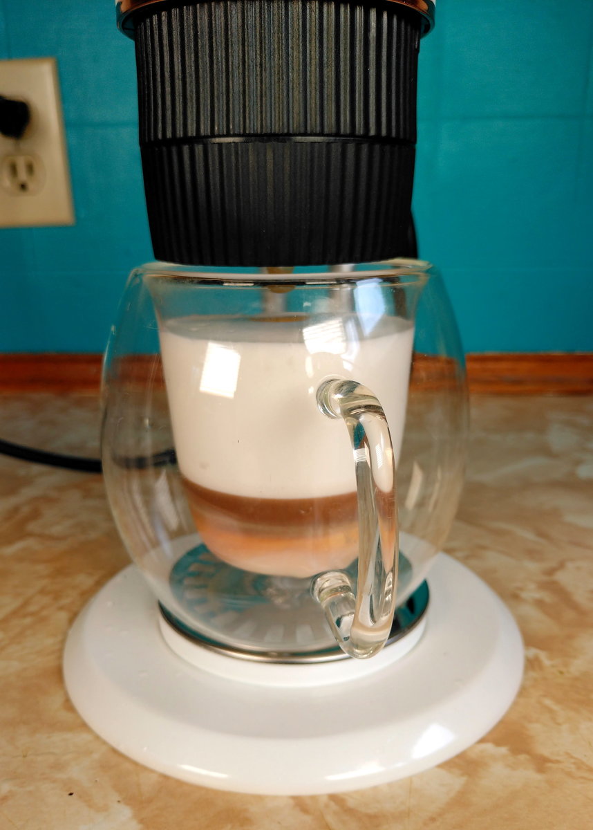 Adding a shot of espresso to a cup of foamed milk