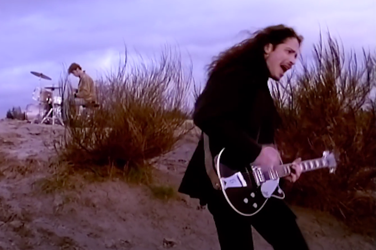 Chris Cornell singing and playing guitar in the "Hunger Strike" music video. In the background is drummer Matt Cameron.