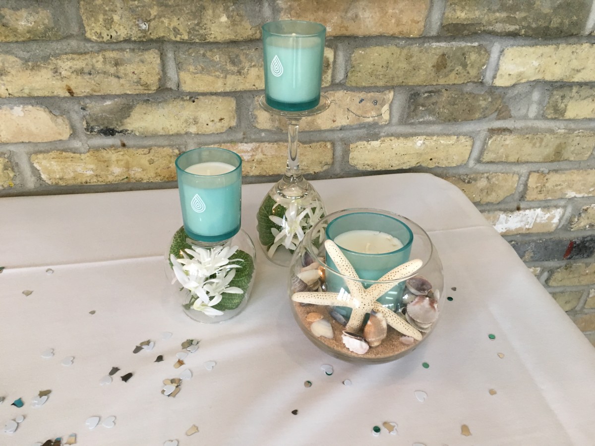 Place flowers in up-side-down wine glasses and put candles on top. Partially fill a glass bowl with sand, place a candle inside, decorate with small shells and stand a star fish in front of the candle!