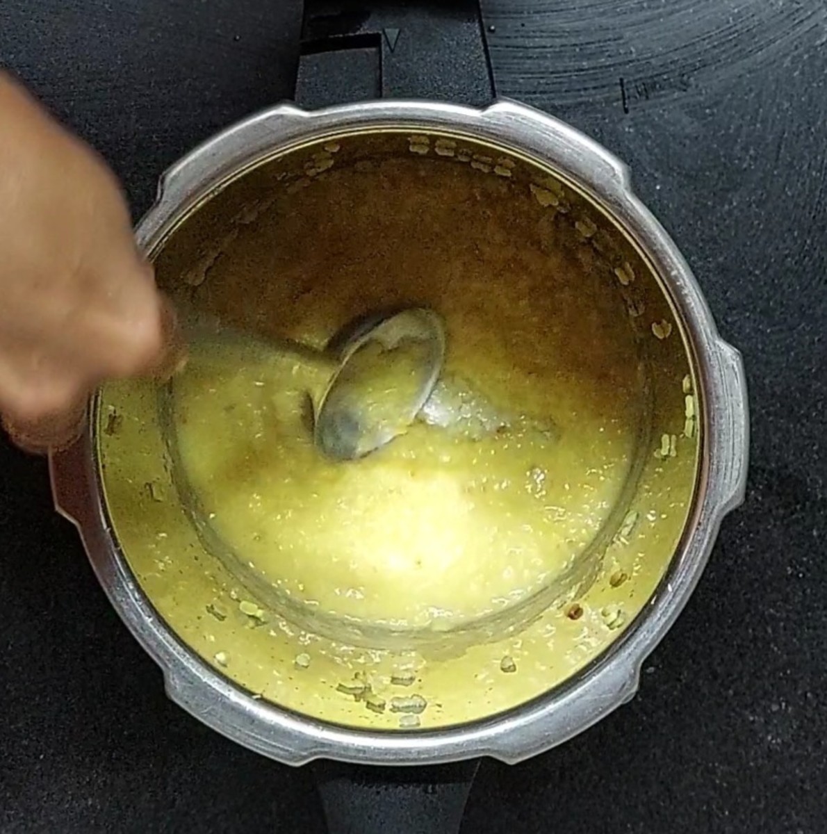 When the pressure of the cooker subsides on its own, open the lid, slightly mash the dal and set aside.