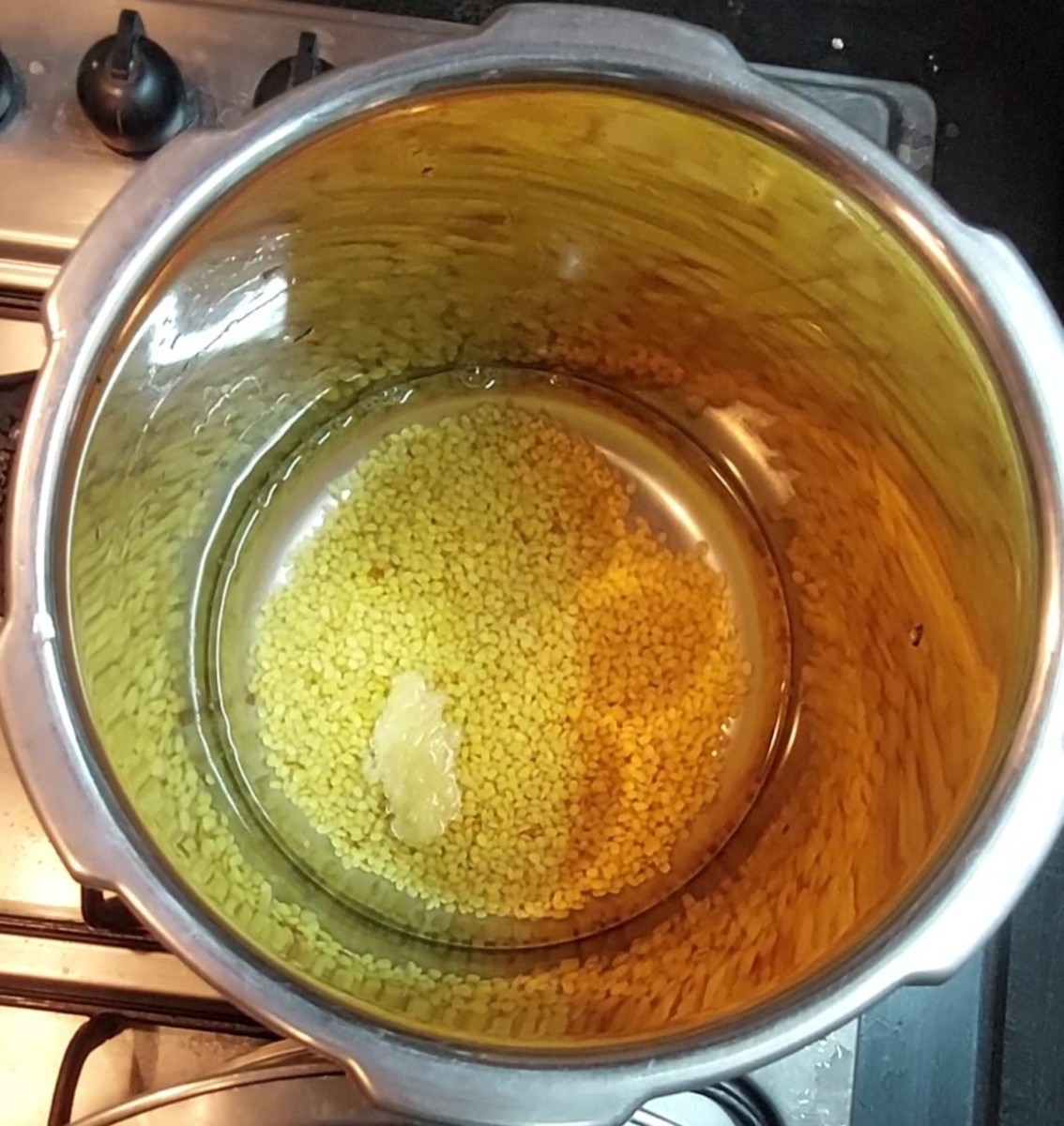 Rinse the dal well. Add 1 cup of water and 1/2 teaspoon ghee, close the lid of the cooker and take 3 whistles. Switch off the flame and let the pressure of the cooker settle on its own.