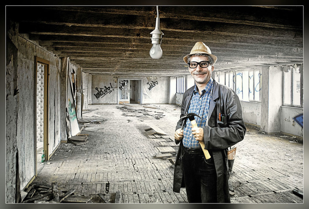 Man poses with a hammer inside a fixer-upper. 