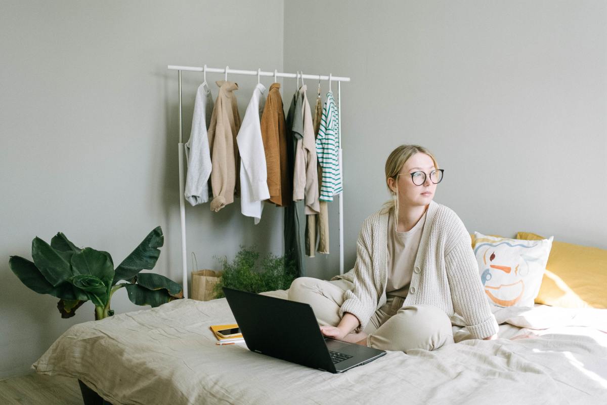 Woman in pajamas works from the comfort of her own bedroom.
