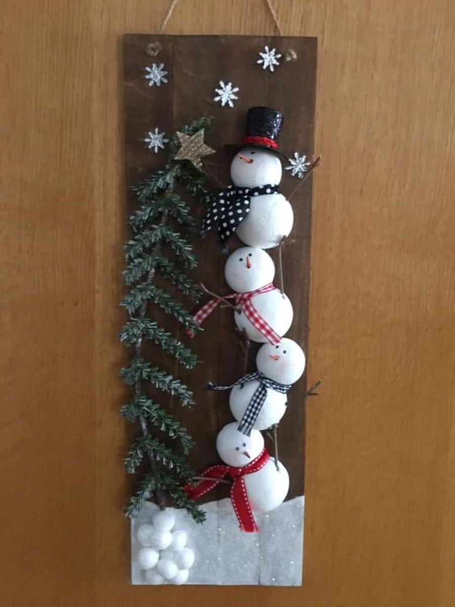 Balancing Snowmen Putting Star on Tree Sign