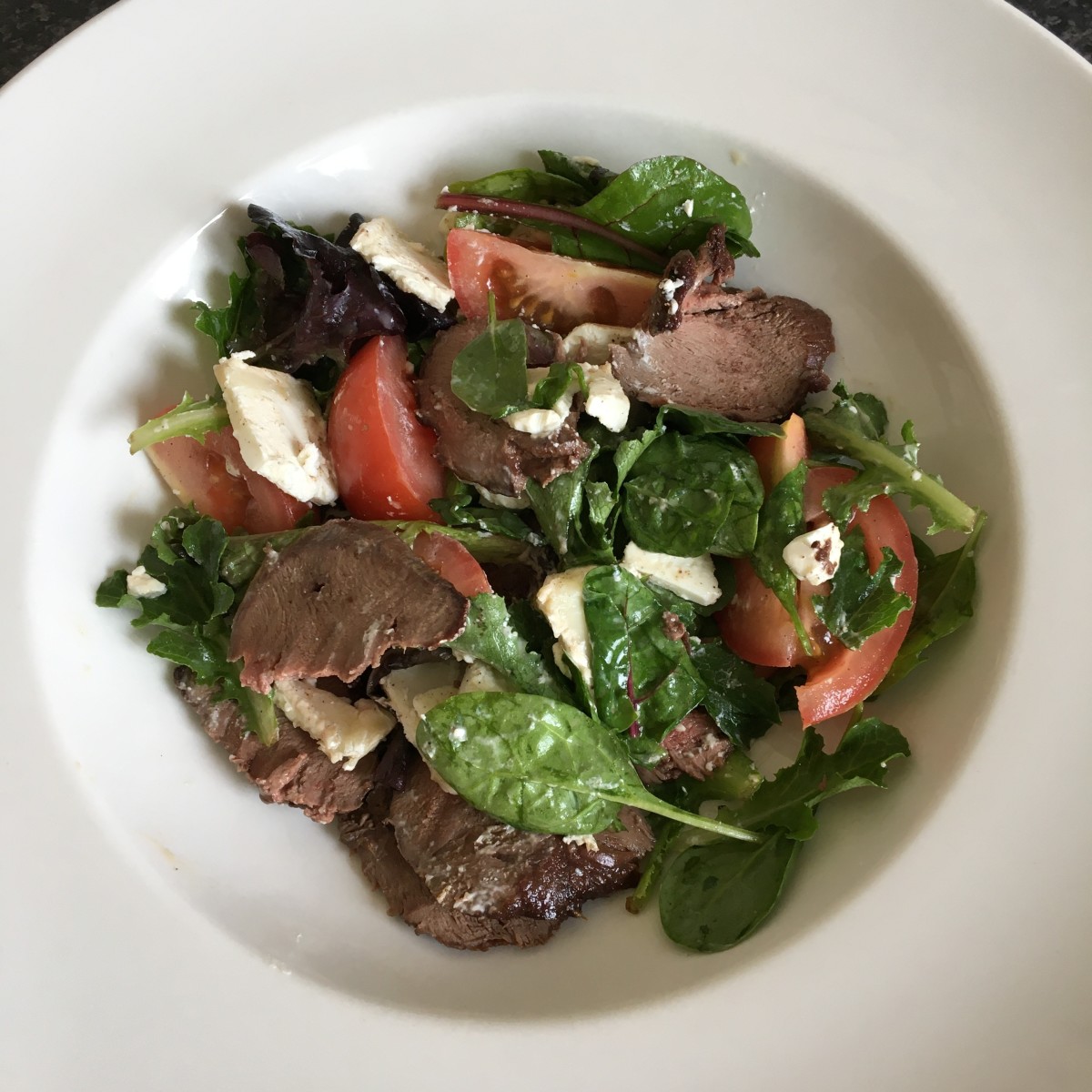Cold pigeon breast flakes and goat cheese in a mixed leaf salad