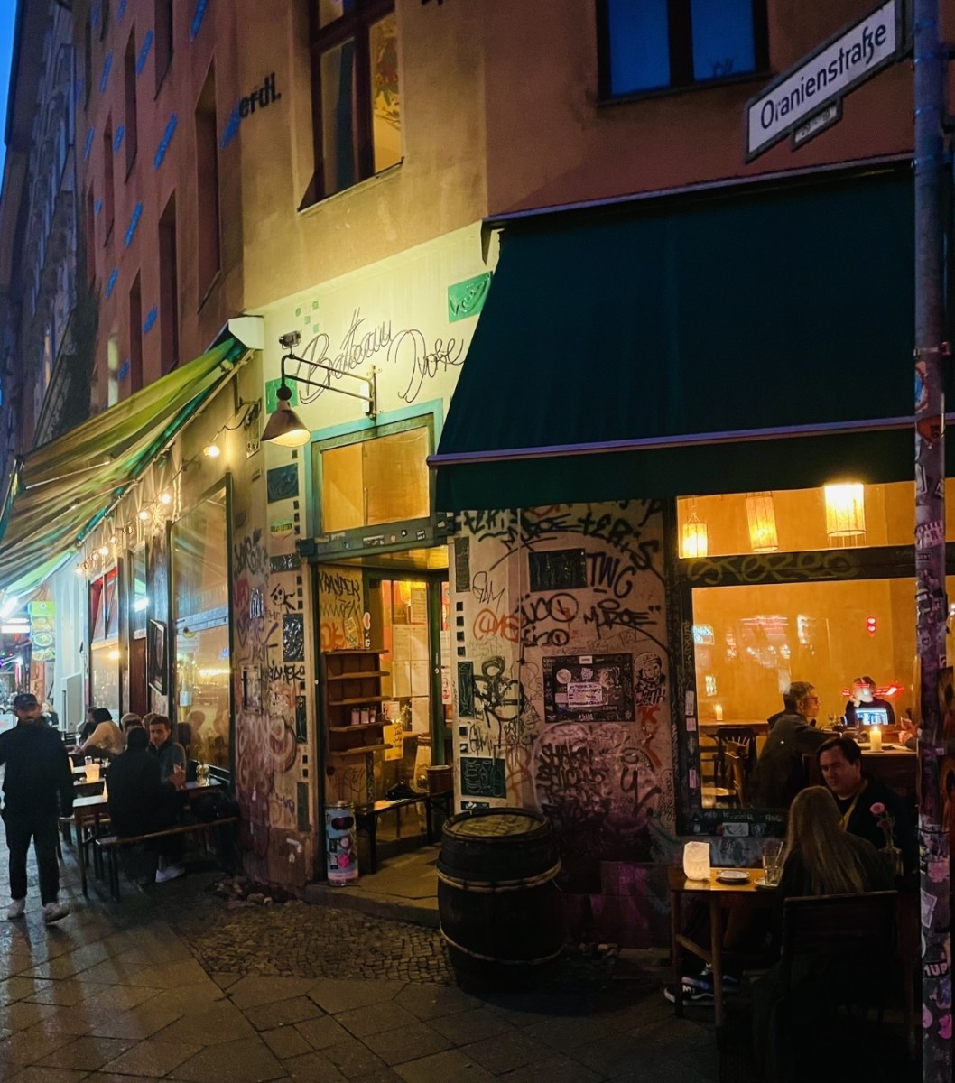 The multicultural Kreuzberg buzzes with life throughout the evening and night. Here from a cafe at Heinrichplatz. Layer upon layer of graffiti also characterizes the street scene here.