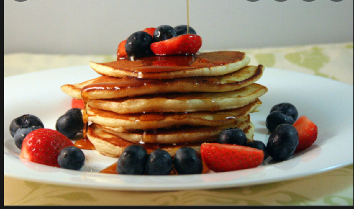Pancakes with honey, strawberry and blueberry toppings.