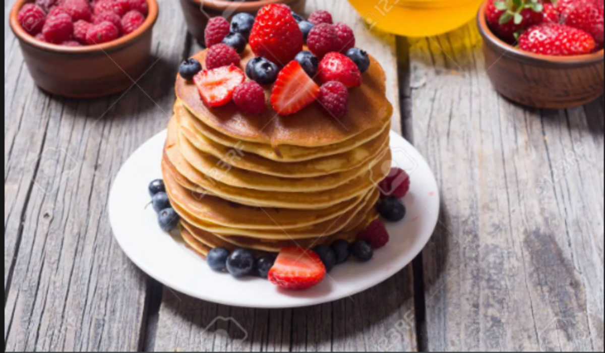 Pancakes with honey, strawberry and blueberry toppings