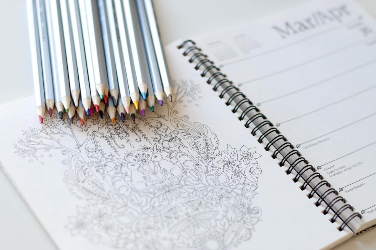 Art materials such as markers and colored pencils are used to fill in line-art drawings or complete activities in coloring books.