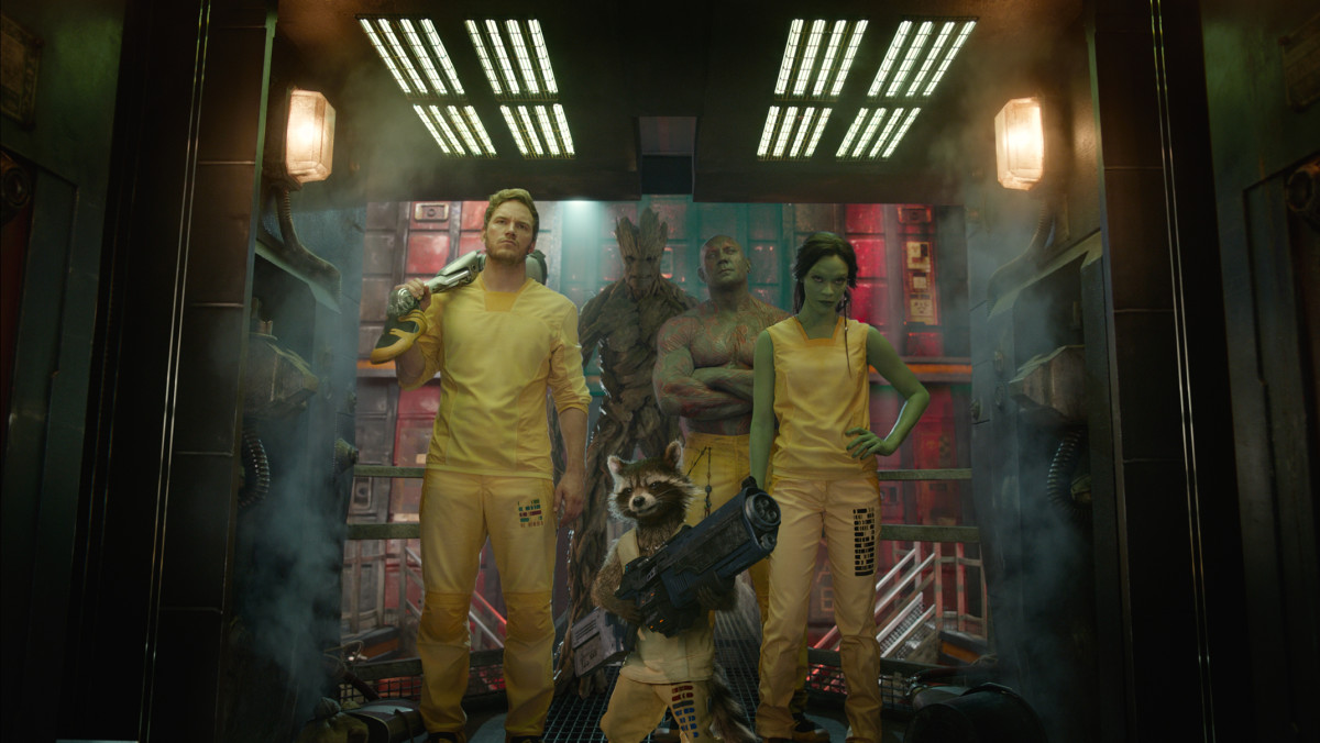 Starlord, Groot, Rocket, Drax and Gamora in full prison uniforms. Weapons aren't prison-issue...