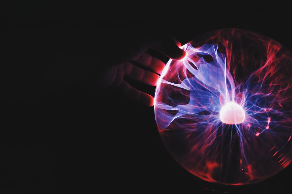 A purple and red electrical static orb, with an inquisitive human hand reaching out in the center. 