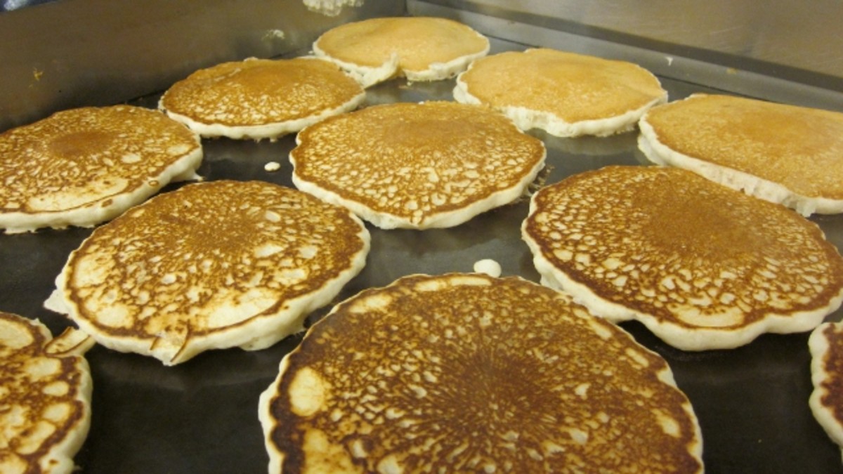 Hot pancakes are served at the Kwanzaa Kitchen Breakfast Program along with scrambled eggs, turkey bacon, grits, juice, and coffee.