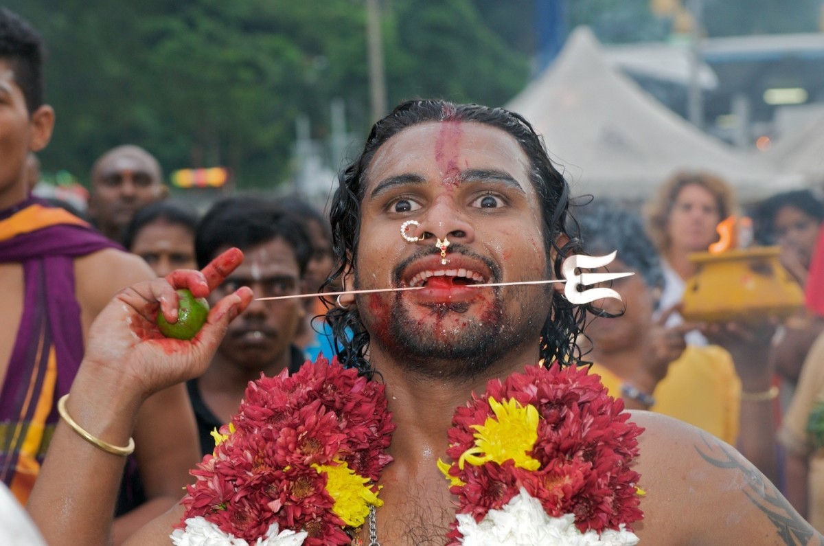 A Thaipusam celebrant with ornaments suspended from hooks piercing his skin