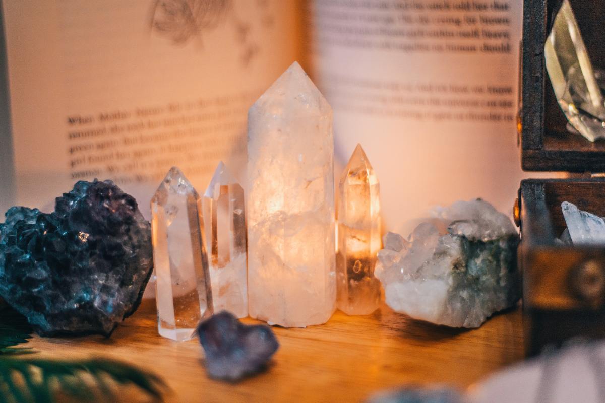 Crystals sit in front of a book on a wooden table.