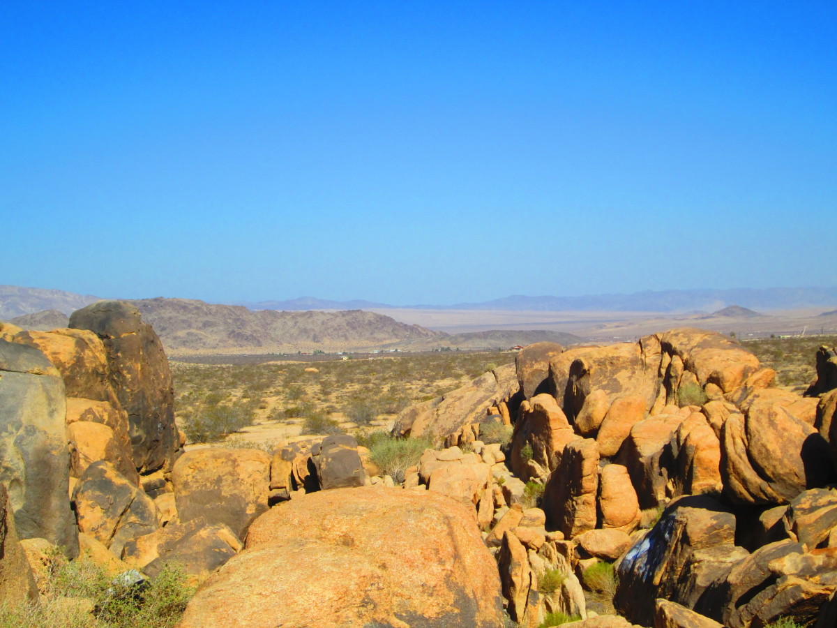 Large tan colored boulders and the vast expanse of desert in the distance.