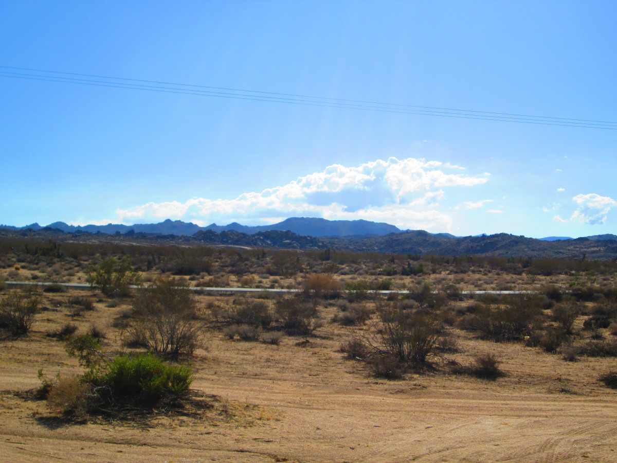 A view from a stop along Old Woman Springs Road. Clouds are floating above the mountains in the distance.