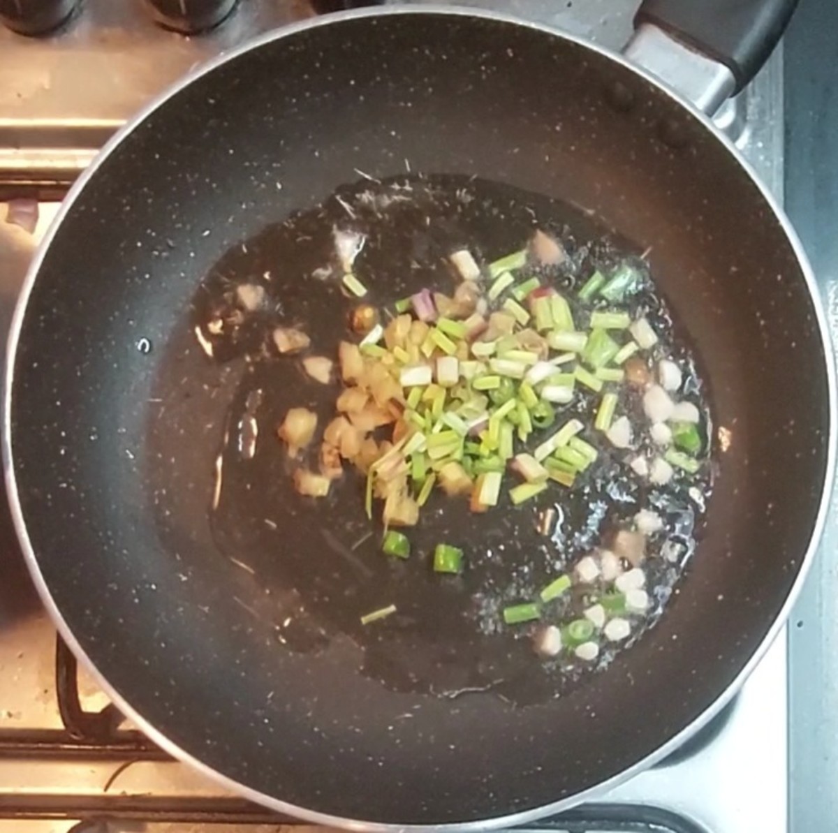 In the same pan, heat 1 tablespoon oil, 1 spoon chopped ginger, 5-6 chopped garlic, 1-2 green chilies, and 1 tablespoon spring onion. Fry well.