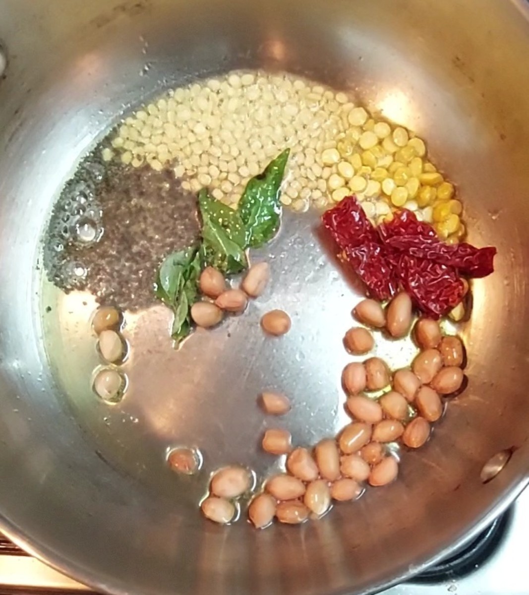 In a pan heat 1 teaspoon ghee and 1 teaspoon oil. Splutter 1/2 teaspoon mustard seeds. Add 1/2 teaspoon urad dal, 1 teaspoon chana dal, 1-2 broken red chilies, a sprig of curry leaves, 1/4 teaspoon hing and 2 teaspoons peanuts.