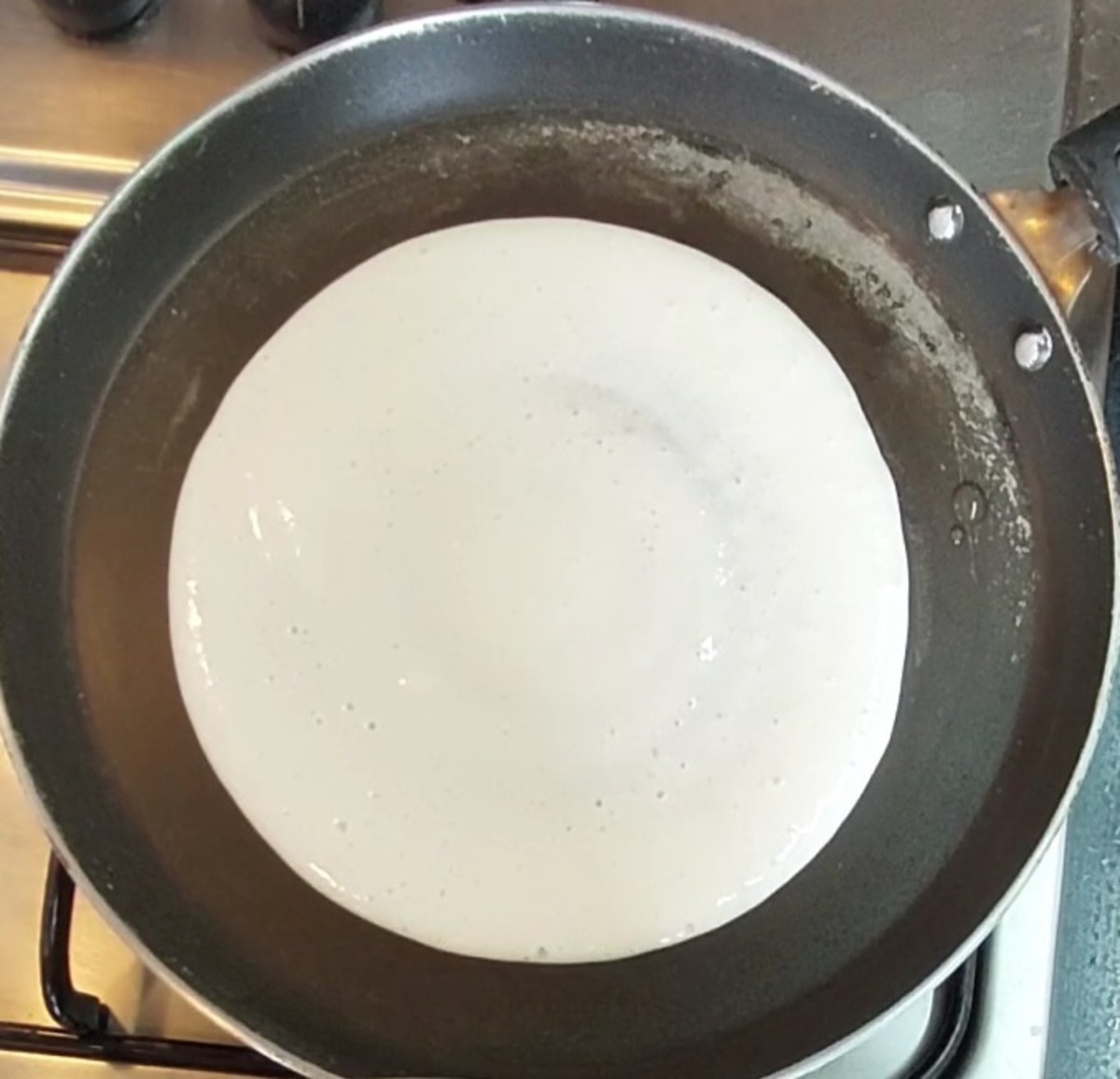 Heat a tawa over medium flame. Take a ladle full of batter and add it to the tawa. Do not spread it too much. Make a thick dosa. Drizzle 1/2 teaspoon of oil on all sides. Close the lid and cook for 1 minute or until it is properly cooked.