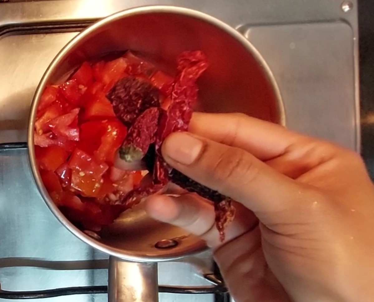 In a vessel, add 1 cup chopped tomatoes and 2-3 red chilies.