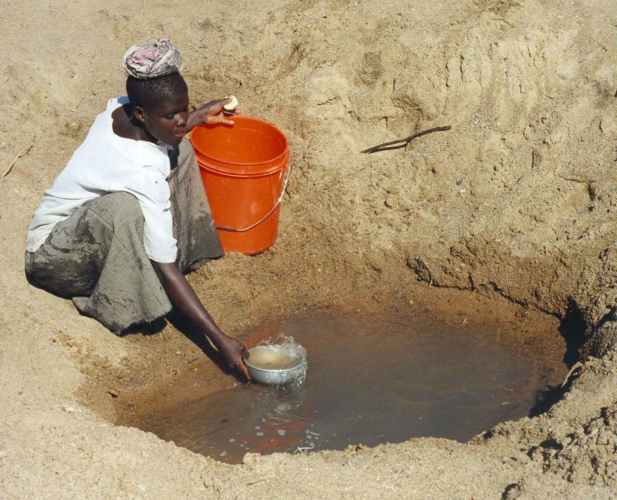 Woman gathering water (most likely contaminated) from a borehole in Tanzania.
