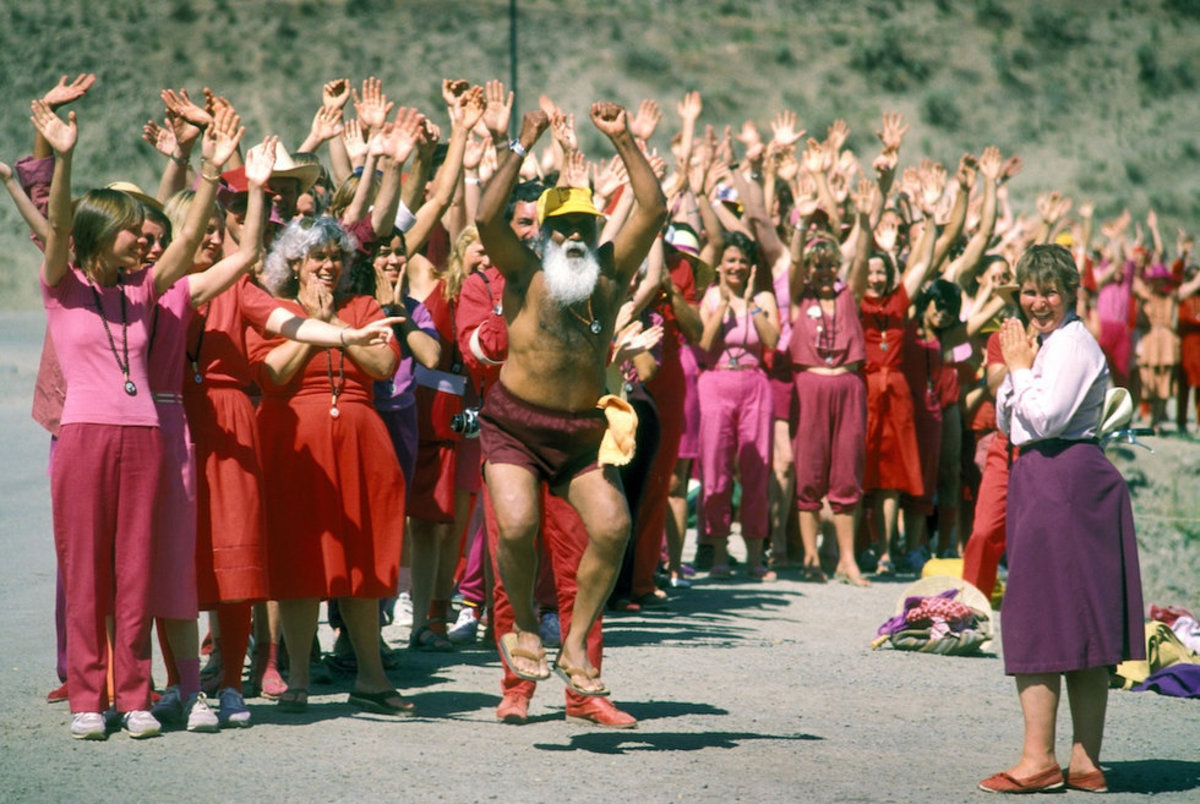Disciples enjoy the antics after lining a commune road for the daily driveby of Bhagwan Shree Rajneesh.