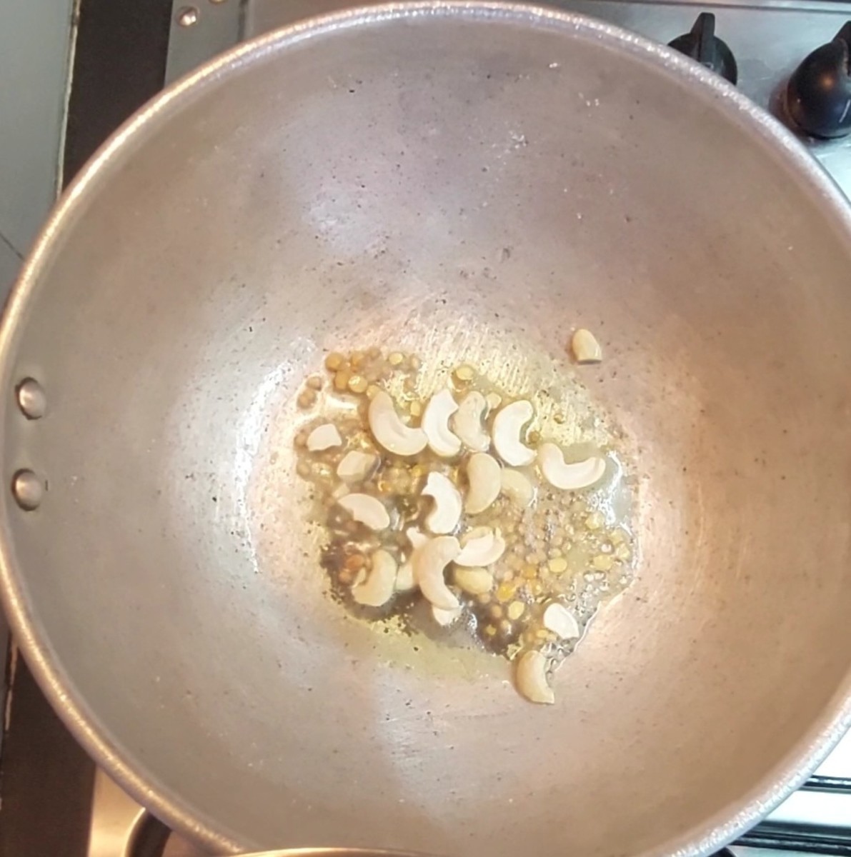 In the same pan, heat 1 tablespoon ghee and 1 tablespoon oil. Splutter 1 teaspoon mustard seeds. Add 1 teaspoon urad dal and 1 teaspoon chana dal and fry for a few seconds. Add 9-10 cashews and fry till they turn golden brown.