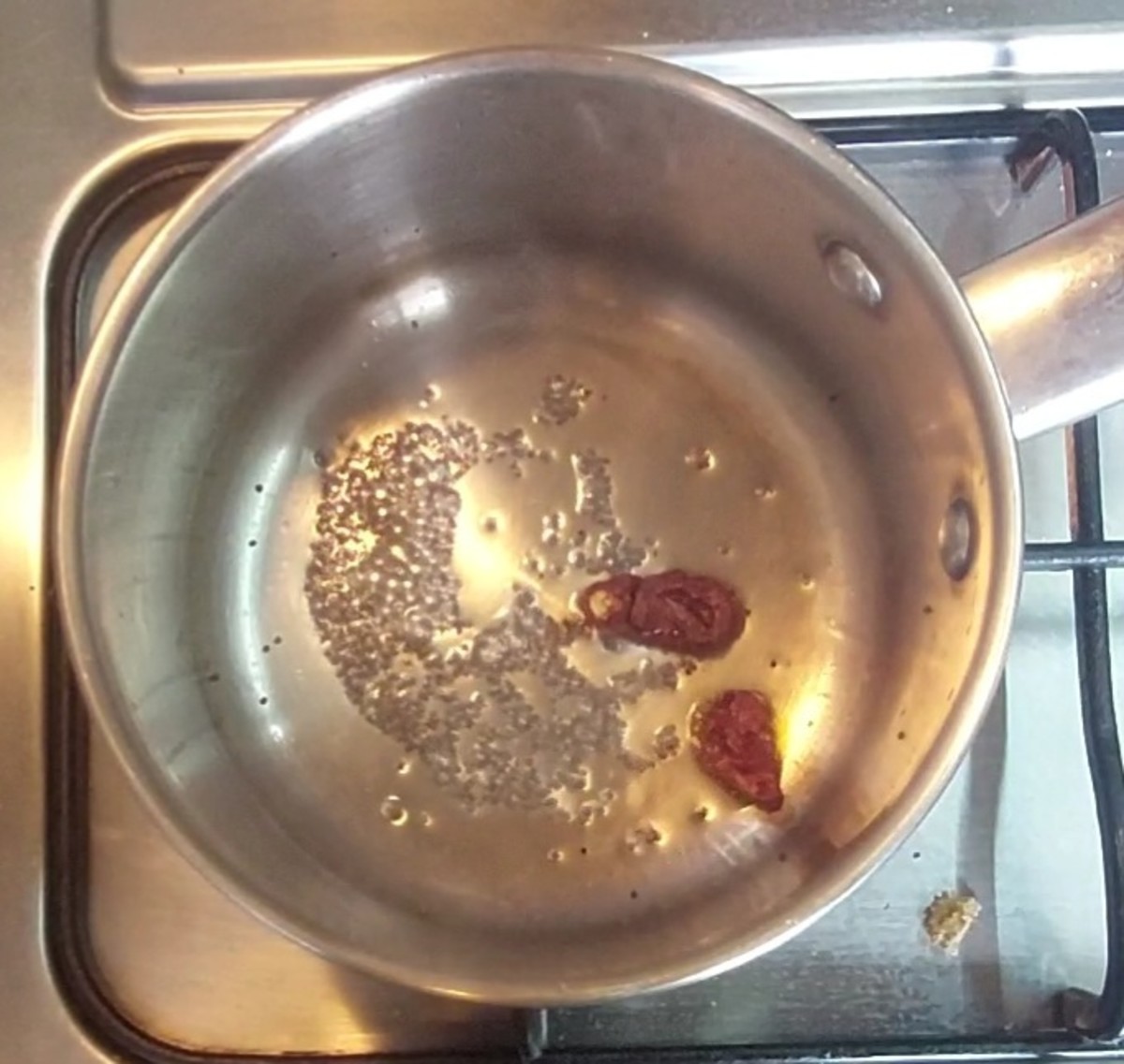 In a frying pan, heat 1 teaspoon oil, splutter 1/2 teaspoon mustard seeds, add 1-2 red chilies, switch off the flame.