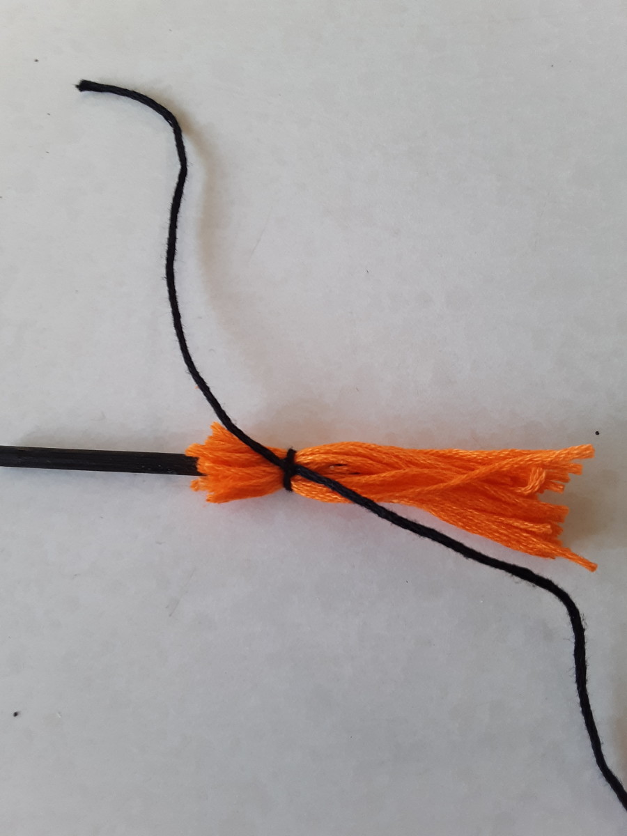 Tie a long piece of yarn around to tighten what will be the bristles to broomstick.