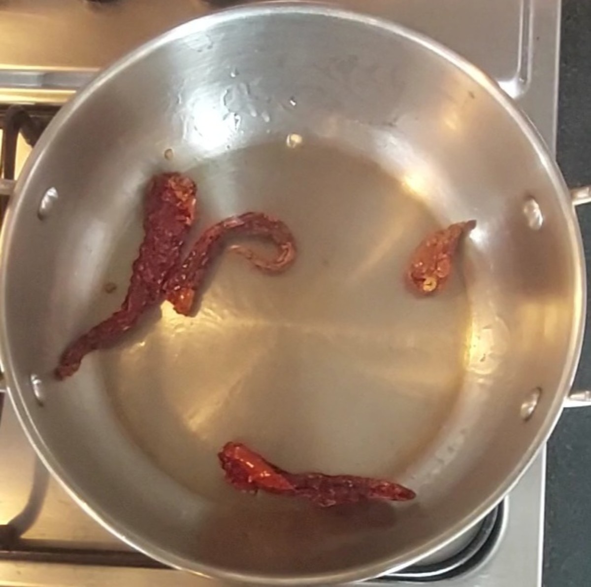 In the same pan, heat 1/2 teaspoon oil, add 2-3 red chilies, fry for a few seconds and transfer to the bowl.