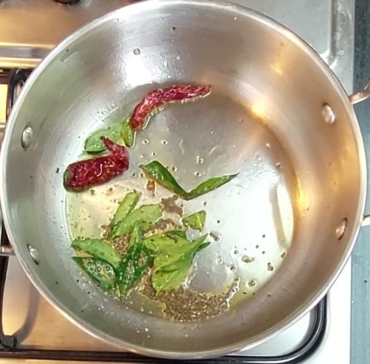 In a pan, heat 1 teaspoon ghee and splutter 1/2 teaspoon mustard seeds. Add 1-2 red chillies, a sprig of curry leaves and 1/4 teaspoon hing. Mix once and switch off the flame.