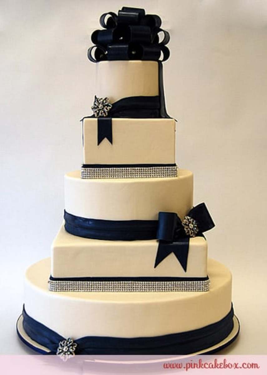 photo credit: pinkcakebox.com Cream colored 5 tier wedding cake with navy blue ribbon