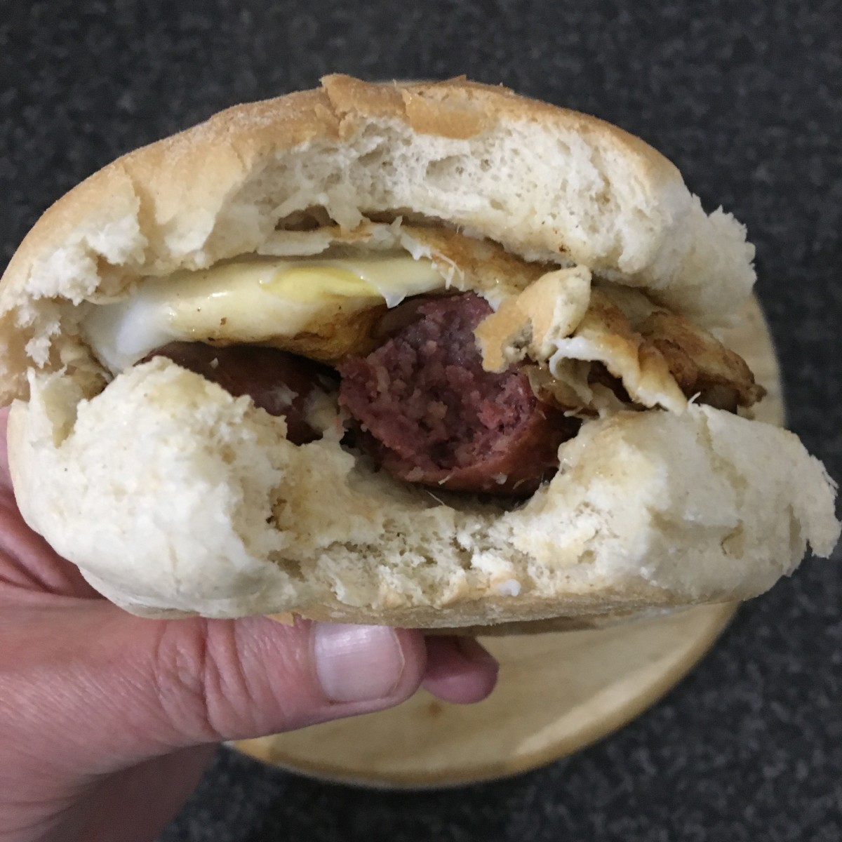 Fried sausage, onion and duck egg on a bread roll