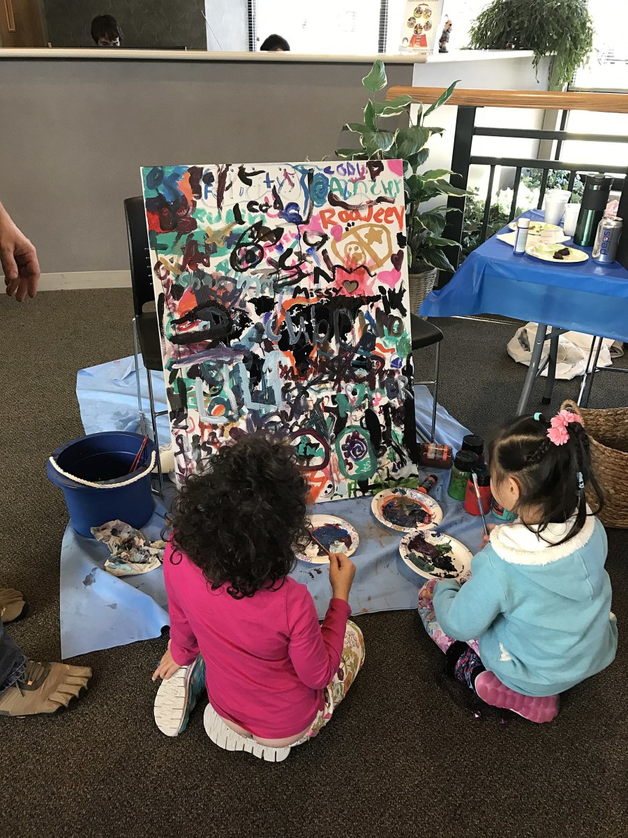 Preschool children painting on a canvas, Jackson Pollack-style.