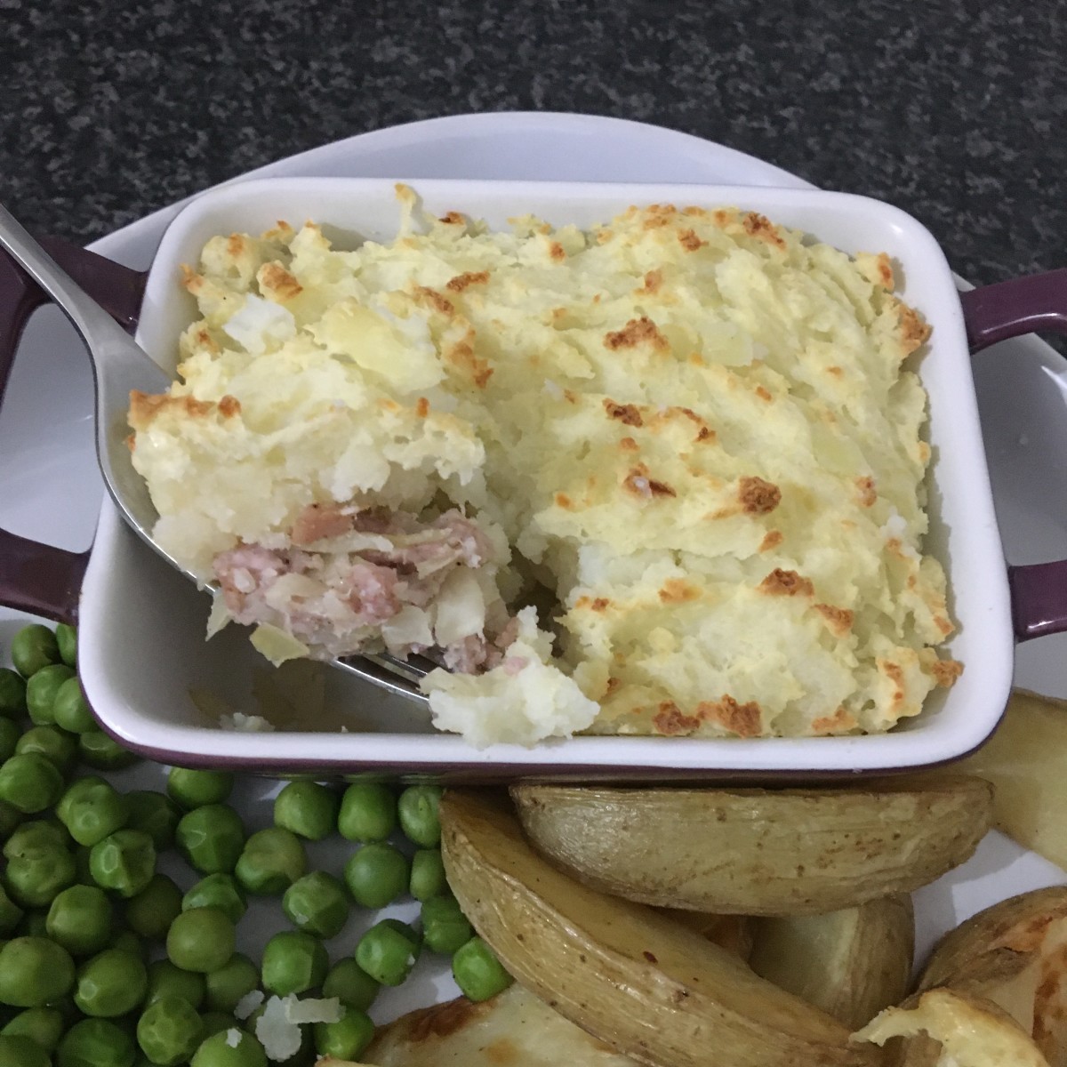 Cabbage and bacon swineherd's pie is served with peas and potato wedges