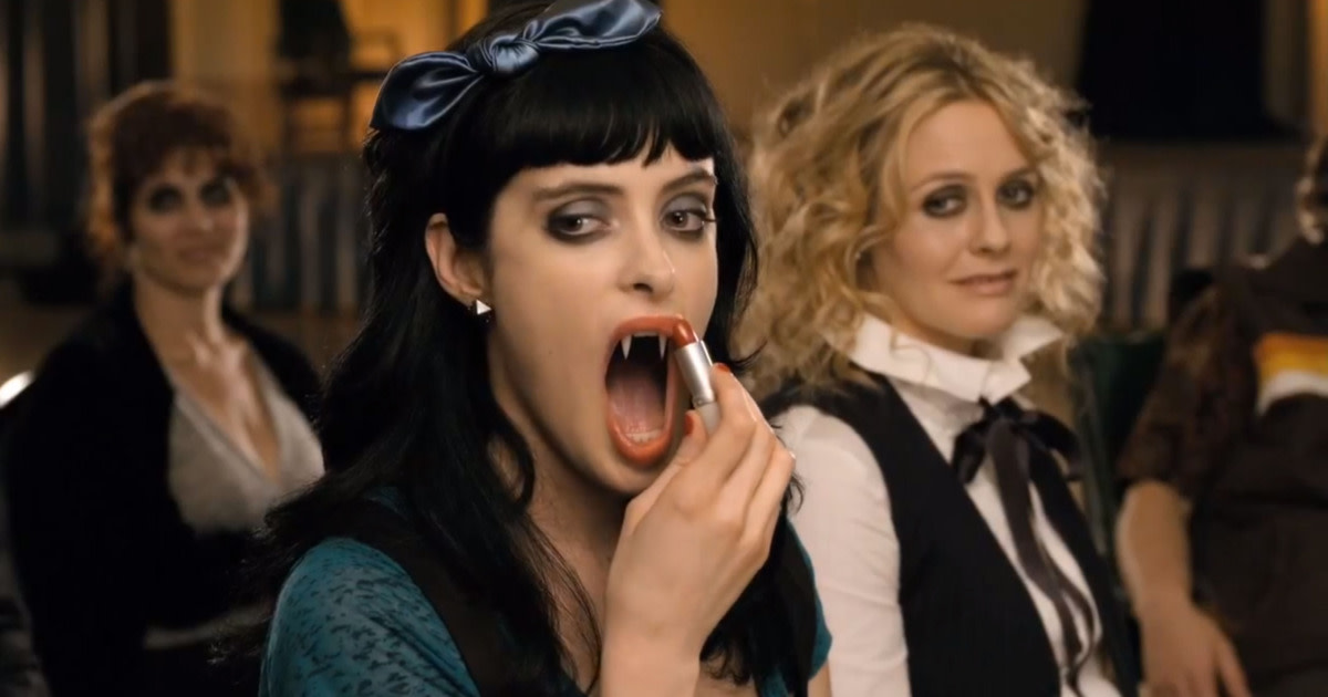 Stacy (Krysten Ritter) scares a participant of a support group while Goody watches on in delight