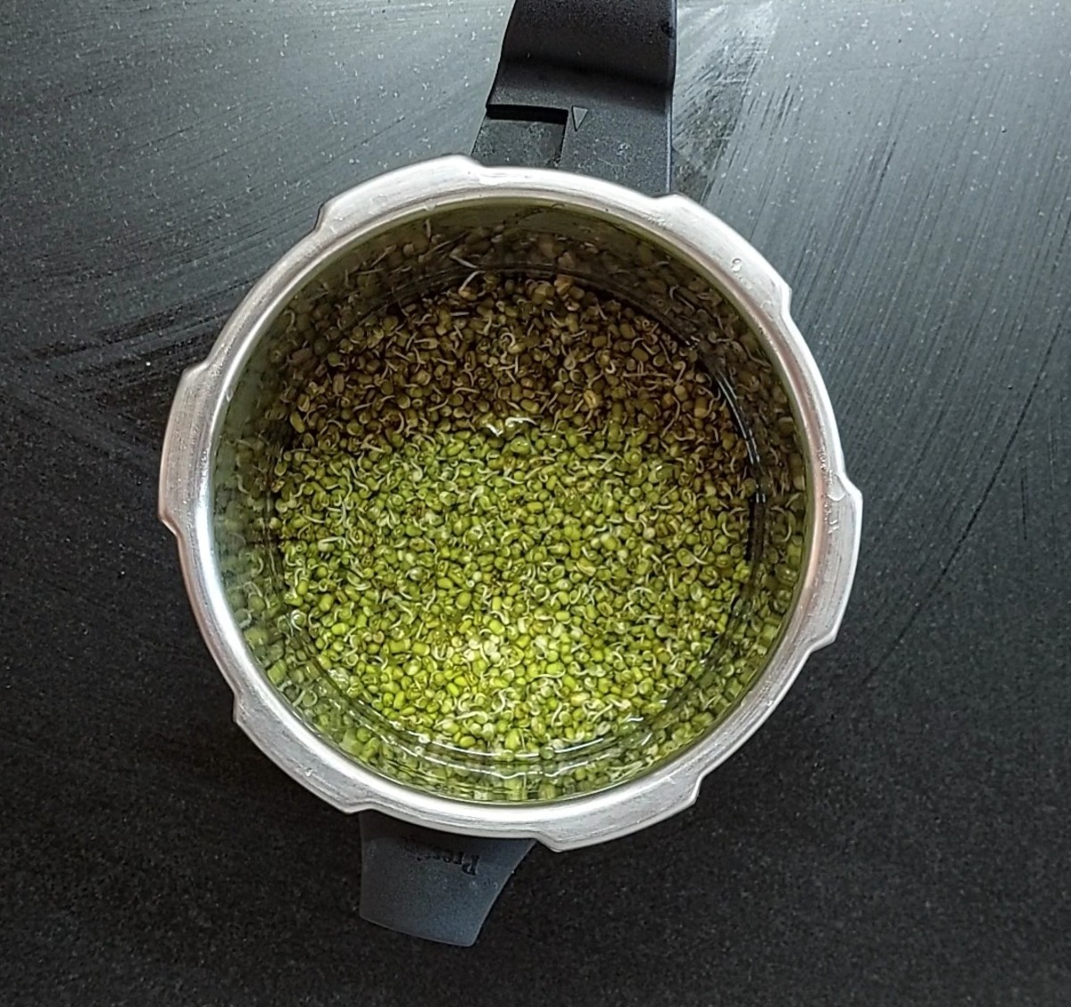 Put 2 cups of sprouted green gram in a cooker and add enough water to submerge the green gram. Add salt, close the lid and take 1 whistle. Switch off and let the pressure subside on its own.