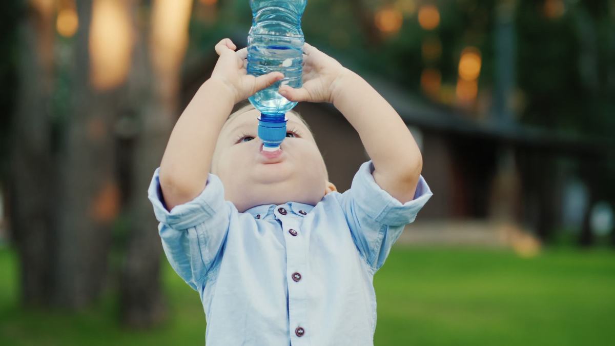 Ребенок год не пьет воду. Малыш на природе с бутылочкой. Ребенок с бутылкой на голубом фоне. Ребенок льет воду из бутылки. Смешной ребенок с бутылкой на море.